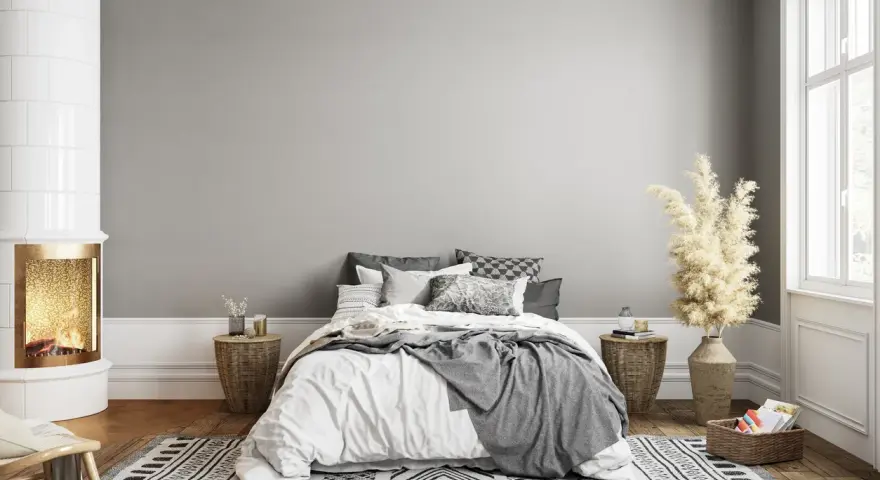 Dormitorio acogedor con chimenea encendida. El gris claro de la pared combina con blanco, negro y tonos tierra, creando un ambiente sereno.