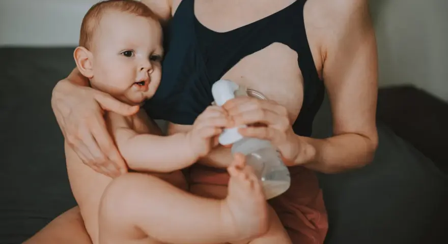 Mama karmi piersią i odciąga pokarm, pokazując, jak karmienie piersią a praca mogą iść w parze.