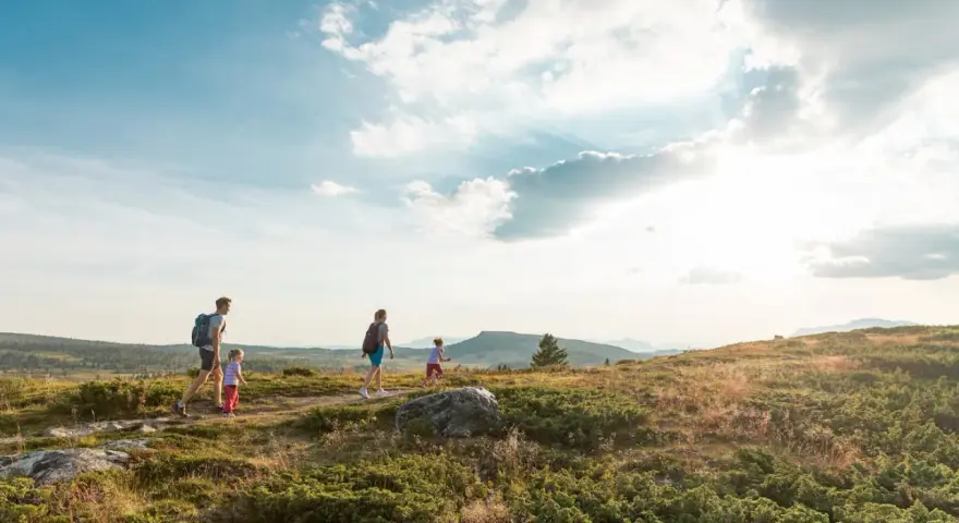 Familj vandrar i solnedgången vid Beitostølen sommar. Barnen springer glatt före föräldrarna genom det kuperade landskapet.