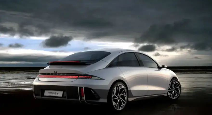 Srebrny Hyundai Ioniq 6 na plaży pod pochmurnym niebem.
