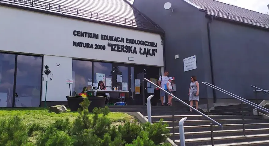 Centrum Edukacji Ekologicznej Natura 2000 "Izerska Łąka" zaprasza. Rodzina wchodzi po schodach do budynku.