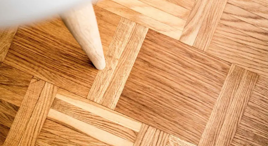 Ett vackert parkettgolv i ek, redo för renovering. En vit möbel står på golvet.
