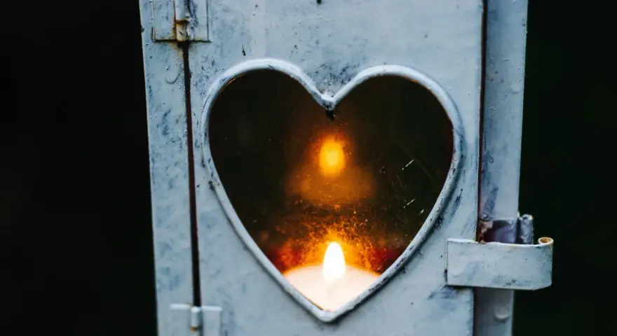 Kerze in Herzform leuchtet. Ein Symbol der Erinnerung an die gestorbene Oma.