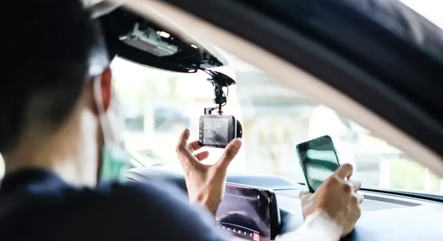 Mann installiert Dashcam im Auto, ADAC-Mitglieder profitieren von sicherer Fahrt.
