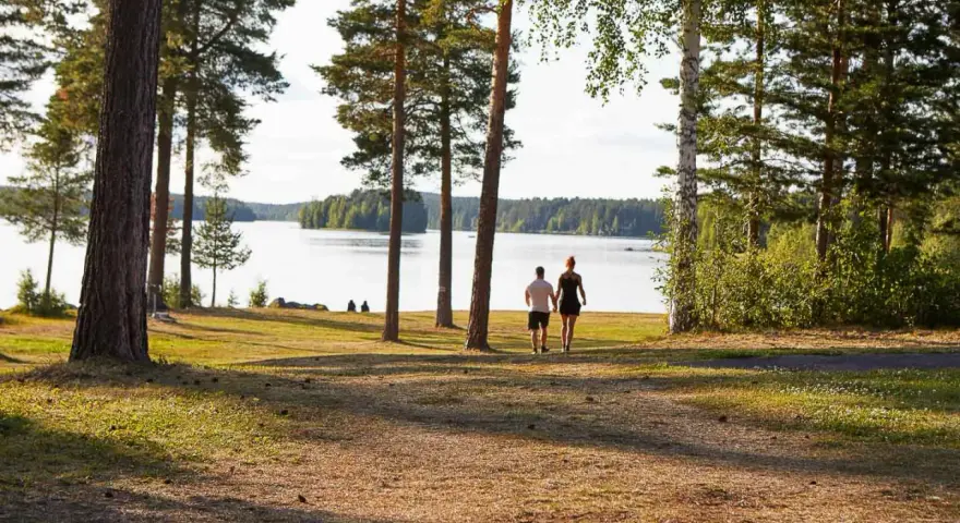 Ett par promenerar hand i hand vid en sjö, en idyllisk plats som påminner om det första camp ansia.