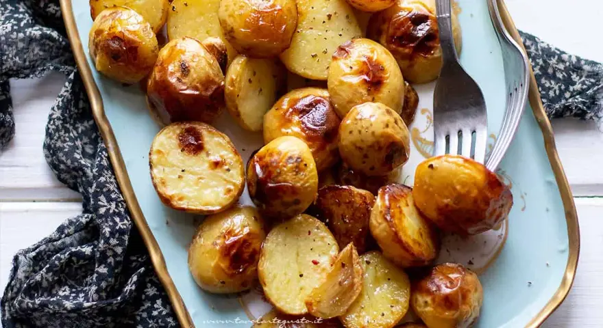 Patate novelle al forno dorate e croccanti, servite su un piatto decorato, pronte per essere gustate.