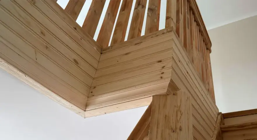 Detalles de la escalera con molduras de madera en la pared, creando un acabado rústico y acogedor.