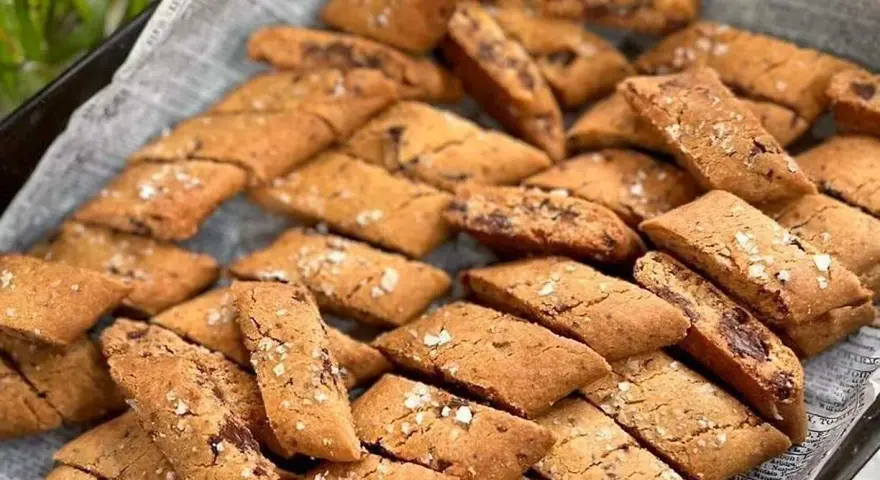 En hög med gyllene kolakakor med chokladbitar och flingsalt. Perfekt för ett enkelt kolakakor recept.