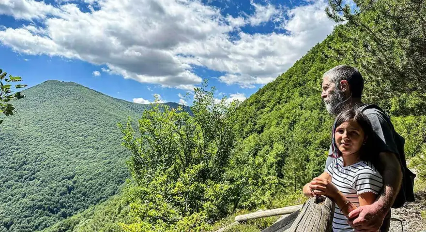 Un uomo e una bambina ammirano il panorama sui sentieri di Roccaraso, immersi nel verde lussureggiante delle montagne.