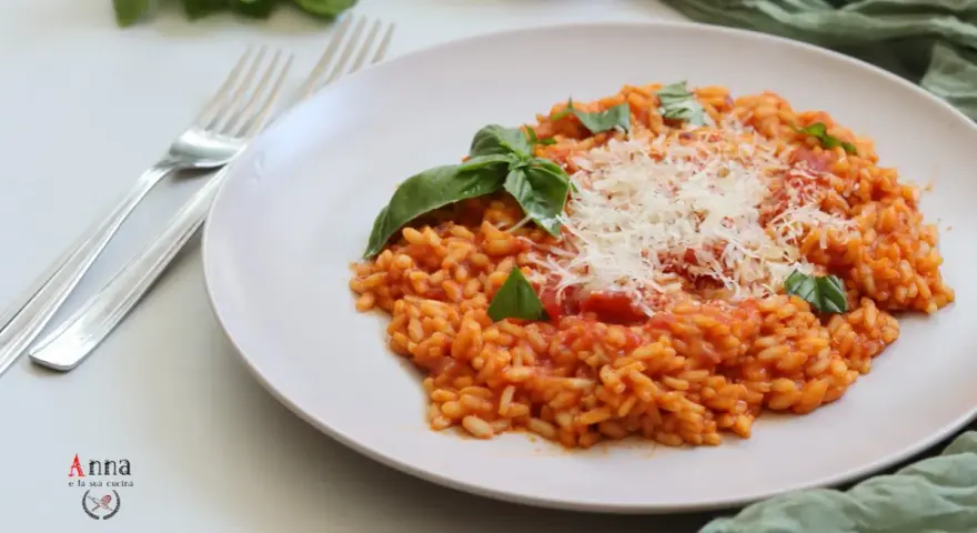 Un cremoso risotto al pomodoro, guarnito con basilico fresco e parmigiano grattugiato, pronto per essere gustato.