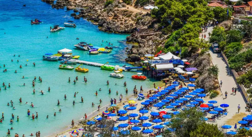 Piękna plaża na Cyprze, pełna ludzi kąpiących się i opalających. Czy na Cypr potrzebny jest paszport z Polski? Nie, wystarczy dowód osobisty.