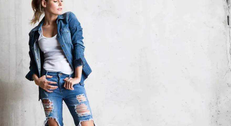Stylowa blondynka w rozdartych jeansach i jeansowej koszuli. Inspiracja, jak nosić koszulę do jeansów.