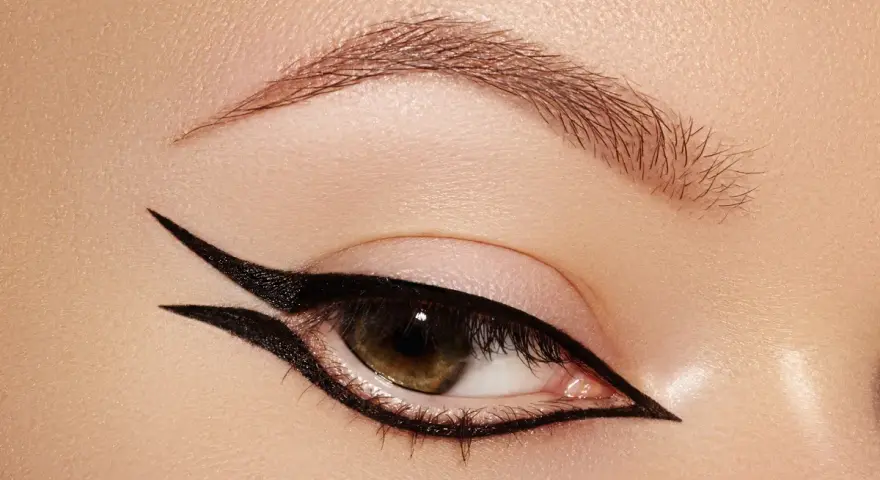 Occhio con un audace **reverse eyeliner** nero, che incornicia la palpebra inferiore e si estende verso l'alto, creando un look grafico e sofisticato.