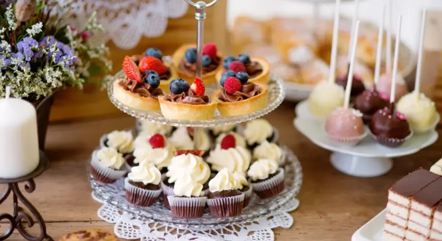 Stół z ciastkami, babeczkami, tartaletkami z owocami i cake pops.
