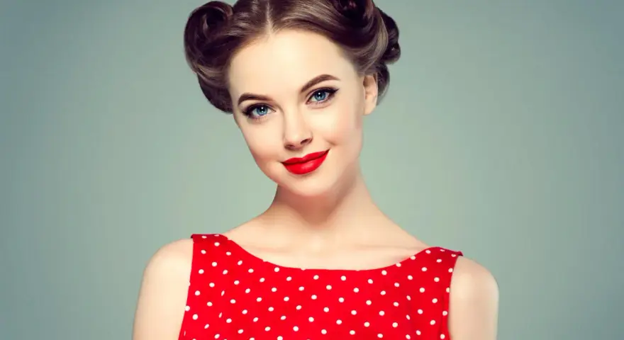 Eleganckie fryzury retro na wesele, z kręconymi kokami i czerwoną sukienką w grochy.