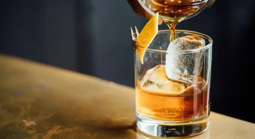 Idealny wieczór: nalewanie whisky z colą do szklanki z lodem i skórką pomarańczy.