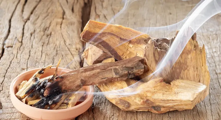 Fragmentos de palo santo humeante sobre madera rústica. Quemar palo santo es malo para el medio ambiente y la salud.