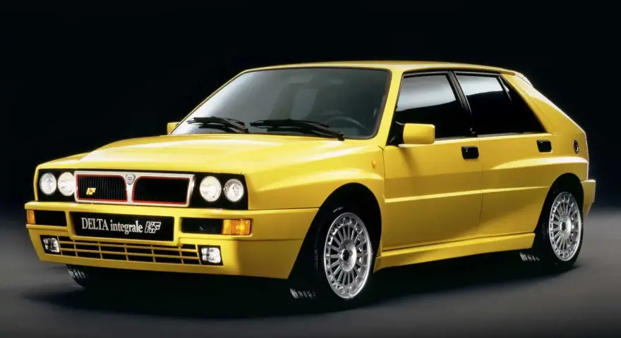 Żółta Lancia Delta Integrale HF z lat 90. na czarnym tle, z charakterystycznym grillem i felgami.