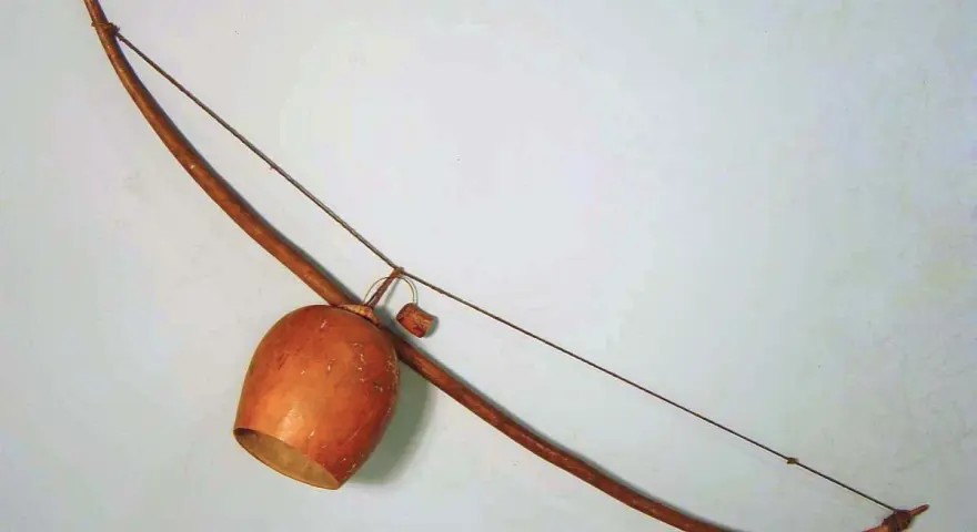 Drewniany łuk muzyczny instrument z tykwą jako pudłem rezonansowym.