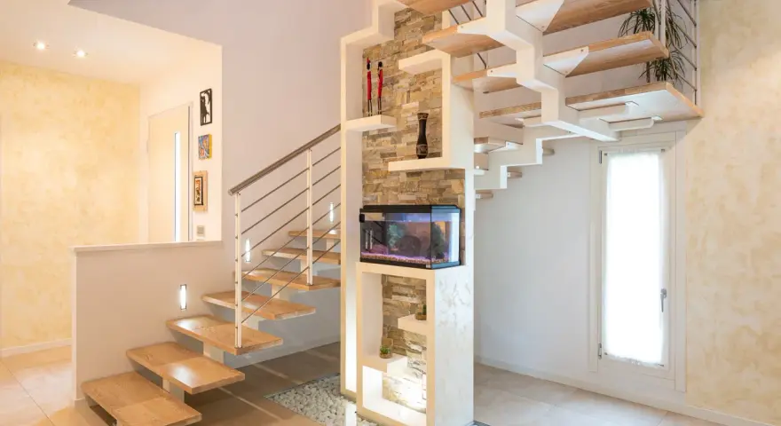 Moderna scala interna in legno e metallo, con acquario integrato e decorazioni in pietra. Un esempio di design che valorizza il costo scala interna.