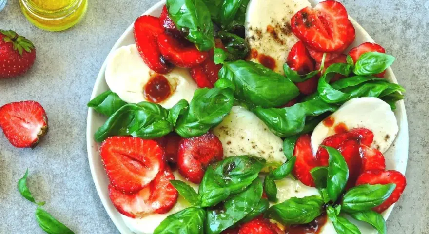 Sałatka z truskawkami, mozzarellą i bazylią. Choć mozzarella zawiera cholesterol, to w tej wersji z owocami i ziołami jest pyszną przekąską.