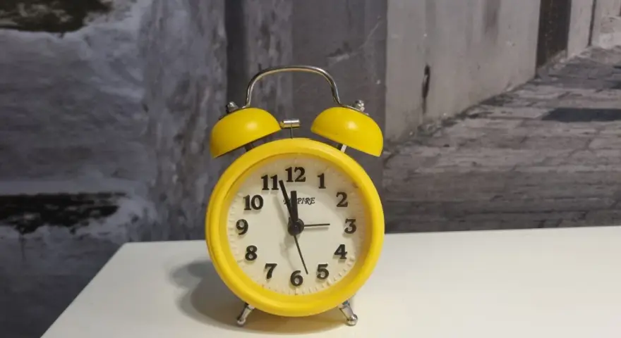 Żółty budzik z dzwonkami, który może oznaczać zakłócanie ciszy nocnej.
