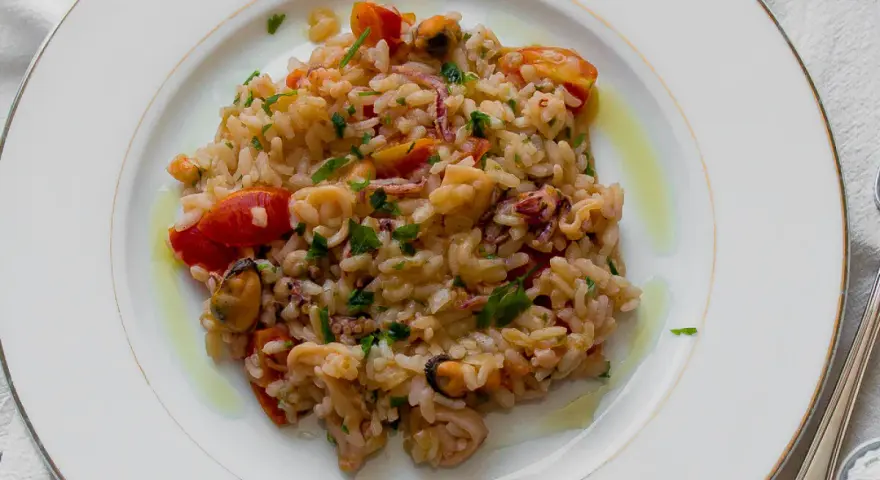 Pyszne risotto z owocami morza, z pomidorkami i natką pietruszki, polane oliwą.