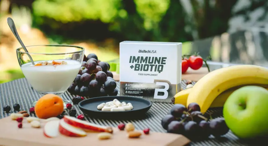Zielone jabłko, winogrona, banany i jogurt z owocami. Obok suplement diety Immune+Biotiq. Idealne na keto.