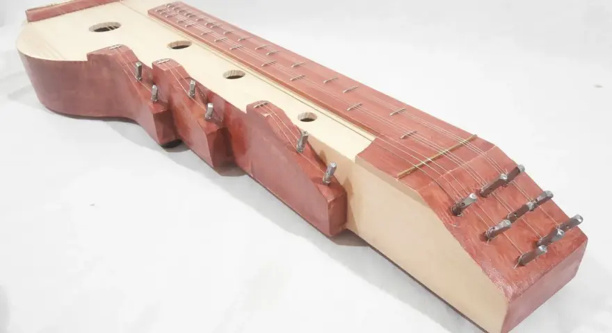 Drewniana cytra instrument z wieloma strunami i otworami rezonansowymi.