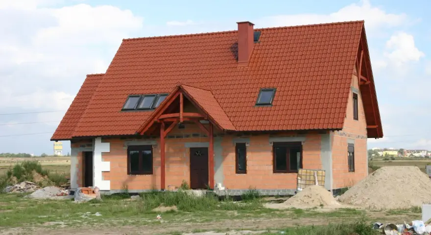 Dom w budowie z czerwonym dachem i oknami dachowymi. Wnętrze z potencjałem na wysoki, **sufit katedralny**.