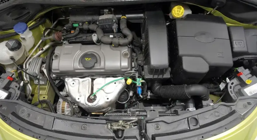 Silnik Peugeot 207, widok z góry. Widać elementy układu dolotowego, pokrywę zaworów i alternator.