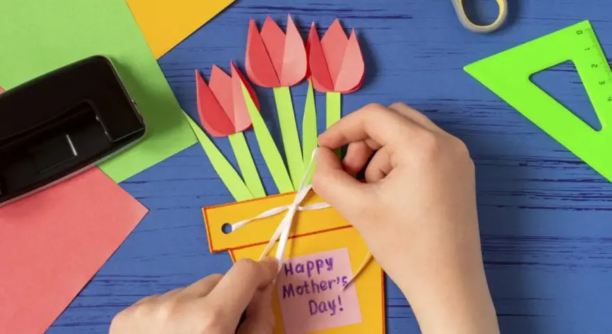 Dziecko tworzy kartkę z tulipanami i napisem "Happy Mother's Day!". To piękne prezenty robione przez dzieci.