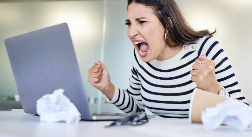 Wütende Frau schreit vor Laptop, frustriert über Probleme im **bad neighbourhood**.