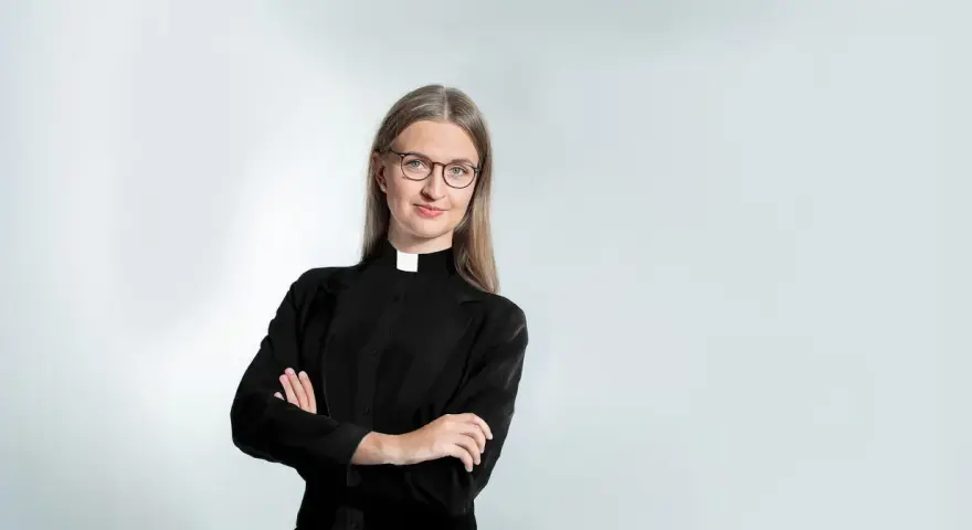 Eine Frau mit Brille und Kragen, die zeigt, dass Pfarrer Beamte sind.