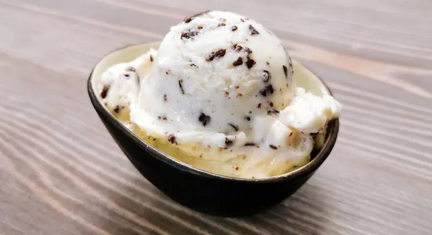 Ein Löffel cremiges Stracciatella-Eis mit zarten Schokoladenstückchen in einer Schale.
