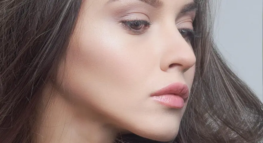 Delikatny makijaż glow podkreślający naturalne piękno. Skóra promienieje subtelnym blaskiem, a usta są muśnięte różowym błyszczykiem.