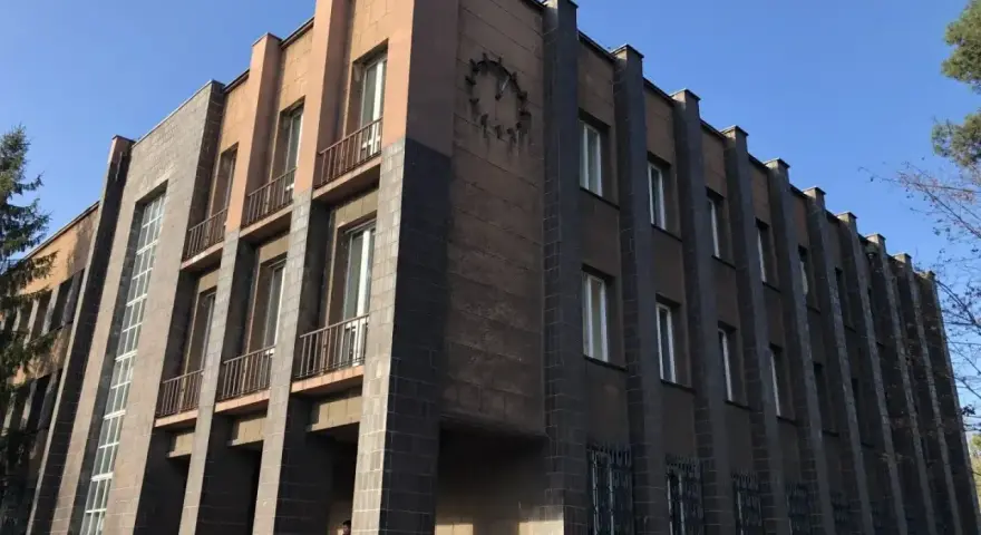 Imponujący budynek w stylu modernizm architektura, z ciemnymi płytkami i jasnymi akcentami, ozdobiony zegarem.