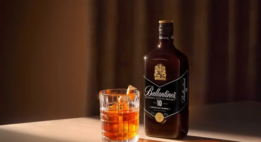 Elegancki drink Rob Roy z whisky Ballantine's 10 Year Old, podany w szkle z lodem i skórką pomarańczy.