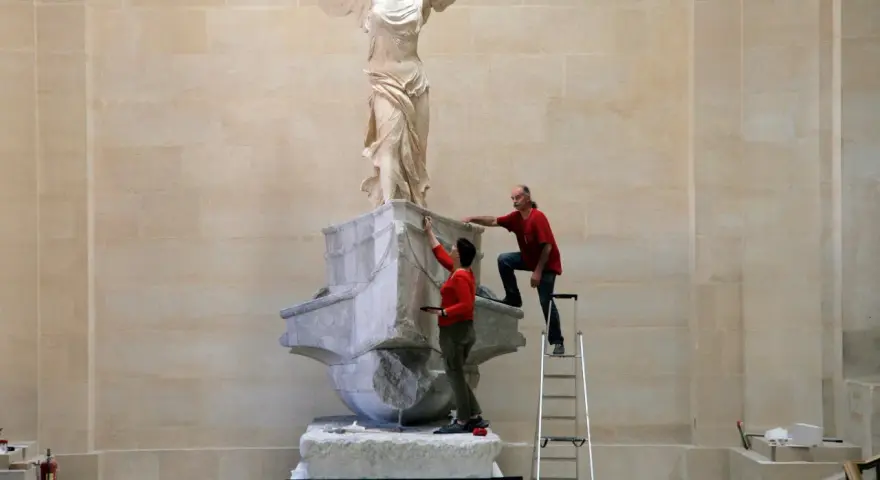 Deux personnes travaillent sur la Victoire de Samothrace, dont la signification symbolise la victoire et la liberté.