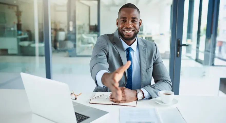 Homme d'affaires souriant, main tendue. Il est assis à son bureau, prêt à conclure un accord, rappelant la jurisprudence sur l'offre d'achat acceptée et la rétractation du vendeur.