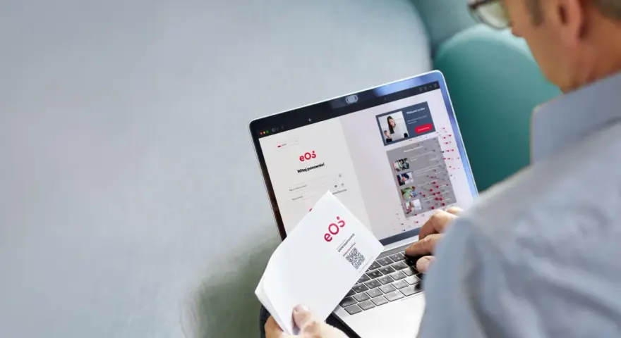 Mężczyzna loguje się do portalu eOS fundusz inwestycyjny. Na ekranie laptopa widnieje formularz logowania i informacje o inwestycjach.