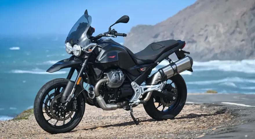 Moto Guzzi V85TT nera, pronta per esplorare, con la sua velocità massima che promette avventure sul mare.