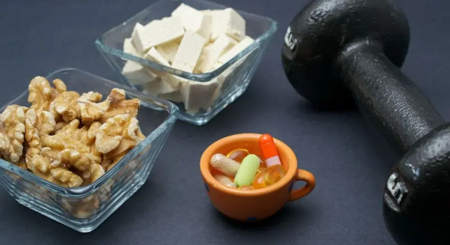 Noix, tofu, haltère et pilules : des éléments pour manger sainement et se muscler.