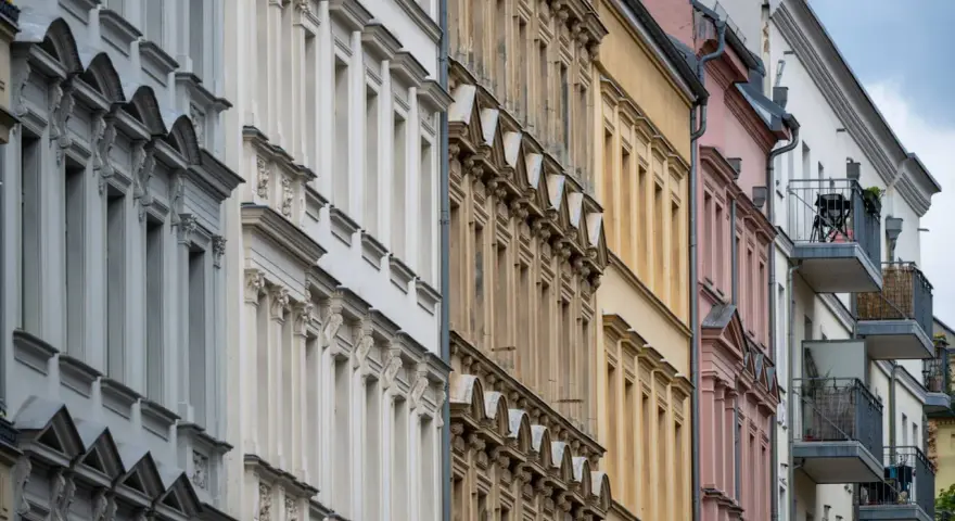Reihenhausfassaden in verschiedenen Farben, von Grau über Beige bis Rosa. Ein Blick auf den m2 preis wohnung in dieser Gegend.