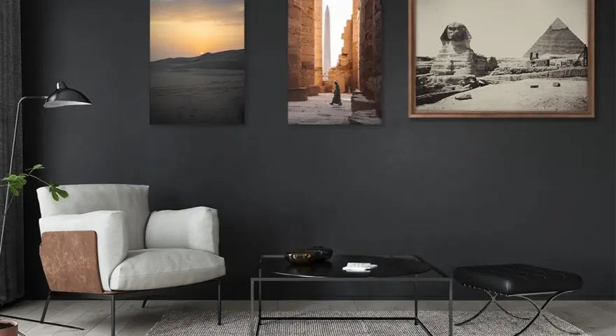 Trois tableaux sur un mur sombre : un coucher de soleil sur les dunes, une personne marchant dans un temple égyptien, et le Sphinx et les pyramides. La **couleur référence** de la pièce est le gris anthracite.