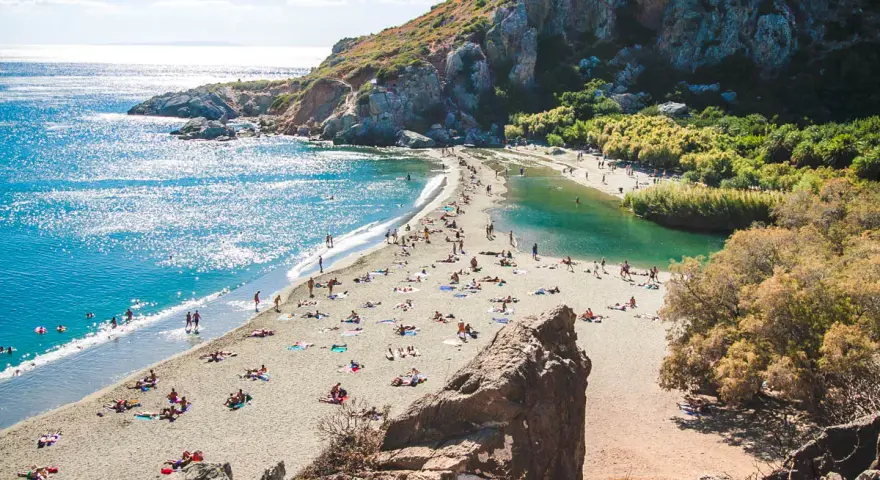 Słoneczny dzień na plaży Preveli. Ludzie odpoczywają na piasku, kąpiel w turkusowej wodzie laguny i morza.