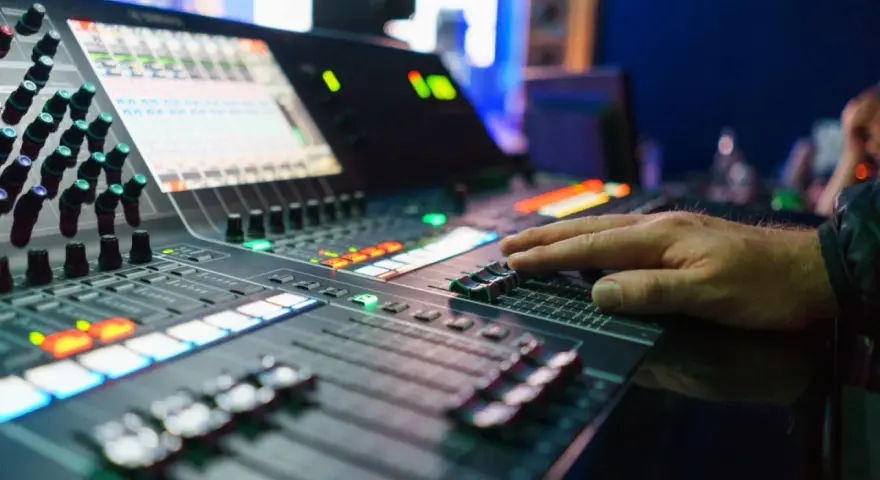 Hand bedient Mischpult für professionelles music management. Lichter und Regler zeigen die komplexe Steuerung.