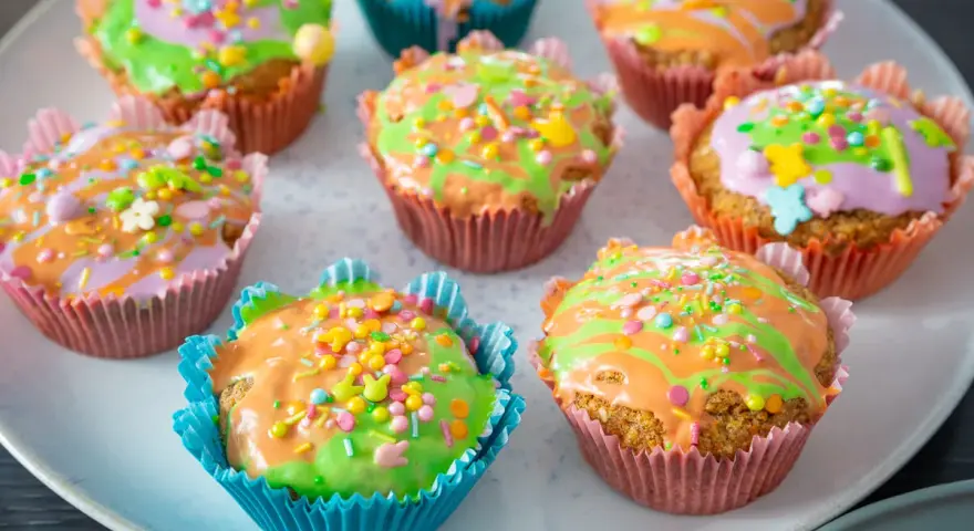 Bunte Karottenmuffins mit Zuckerguss und Streuseln, perfekt für ein Frühlingsfest. Dieses Karottenmuffins Rezept ist ein Hit!
