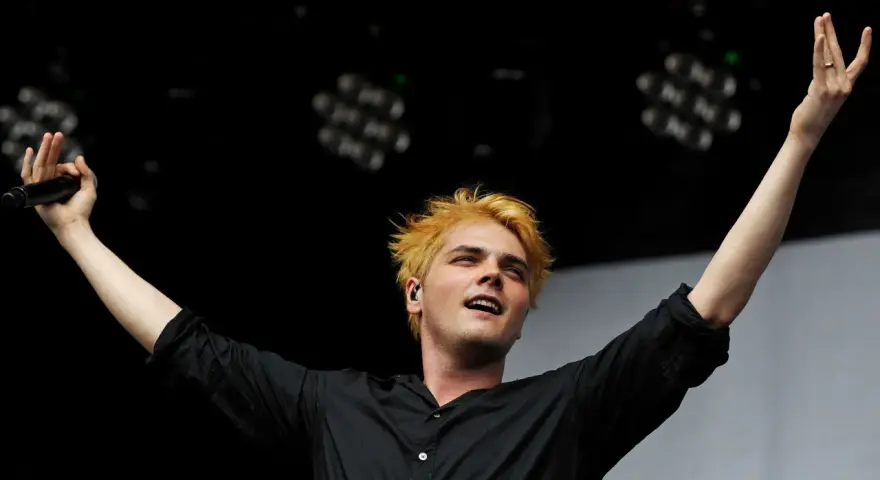 Gerard Way, Sänger des Musikgenres mit E, mit blonden Haaren und erhobenen Armen auf der Bühne.