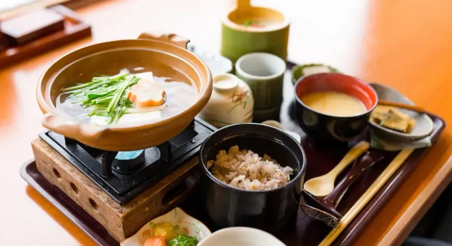 Japońskie śniadanie: gorący bulion z warzywami i tofu, ryż, zupa miso i dodatki.